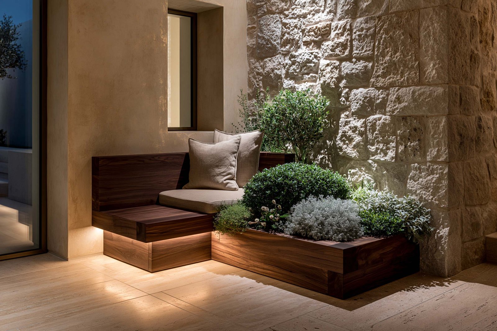 Intimité retirée — niche-alcôve intime dans un coin de villa à Cap-Ferrat au crépuscule, banc bas en noyer fumé sous LED 2700K cachée linéaire, mur en pierre brute calcaire claire à droite et stucco lustro ocre patiné à gauche, planter Lignum™ Block au pied portant Pittosporum tobira nano, Helichrysum italicum et Salvia officinalis en composition basse, sol travertin clair, ambiance feutrée fin de journée, Paracelsus Gardens™