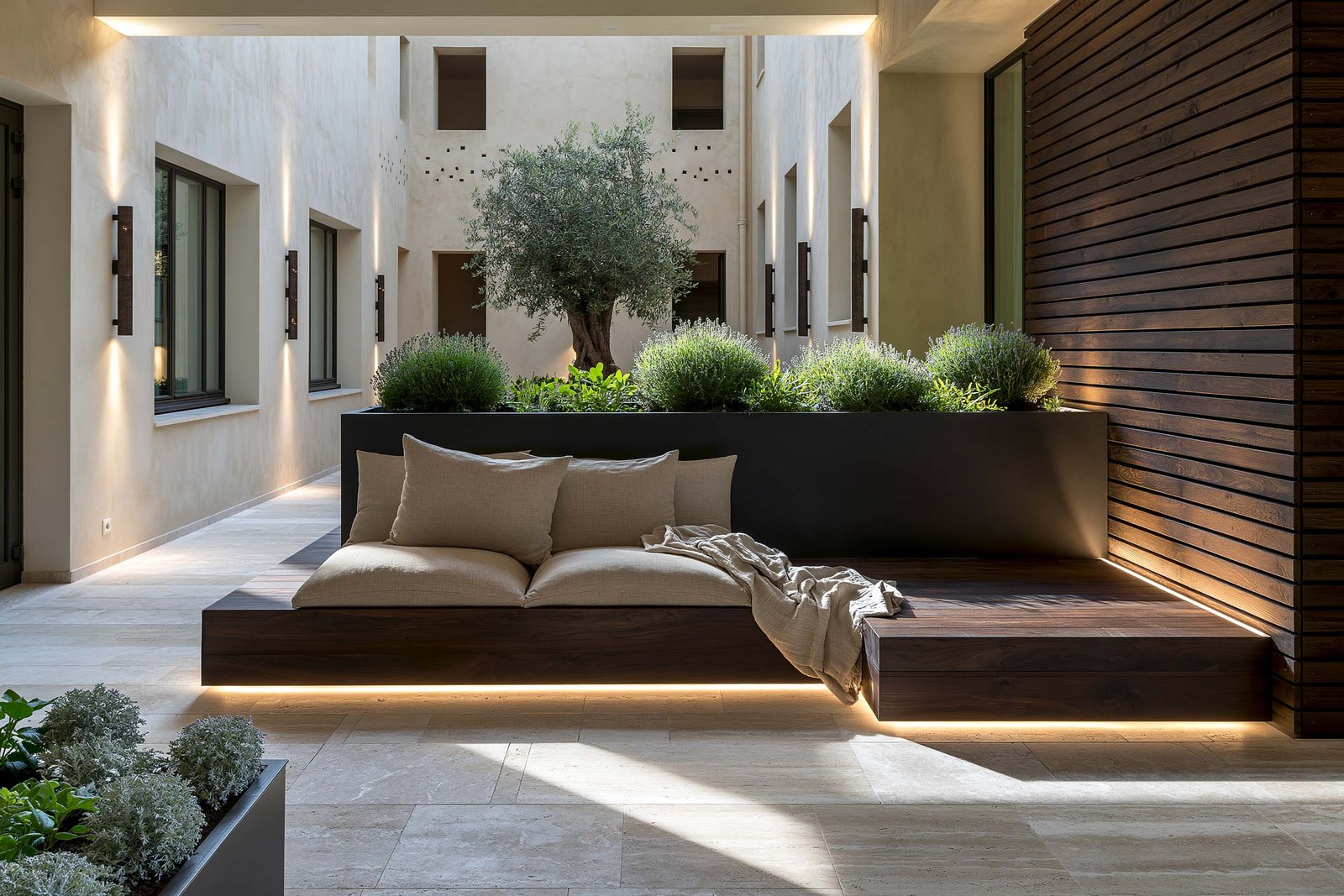 Spa privé à Saint-Jean-Cap-Ferrat, bain immersif en bloc massif Lignum Block en noyer fumé, olivier émergeant d’une Lignum Block carrée taillée dans la masse, mur en stucco lustro chaud rétro-éclairé LED 2700K, peignoir en lin écru.