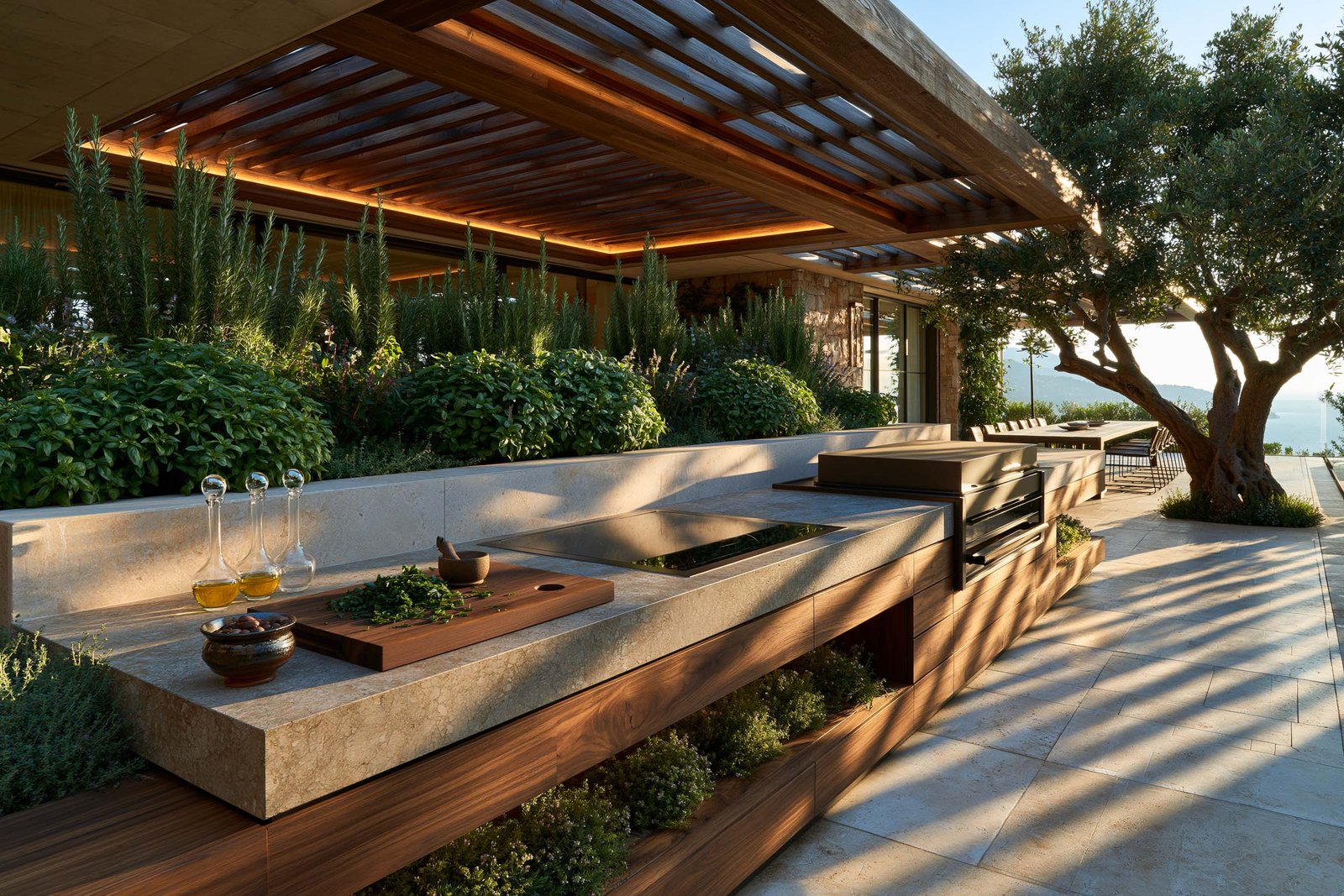 Cuisine extérieure contemporaine d’une villa à Èze, plan continu en Pietra Serena et noyer fumé avec gril intégré, jardinières maçonnées d’herbes aromatiques en port libre, façade en stucco lustro chaud, dallage en travertin clair.