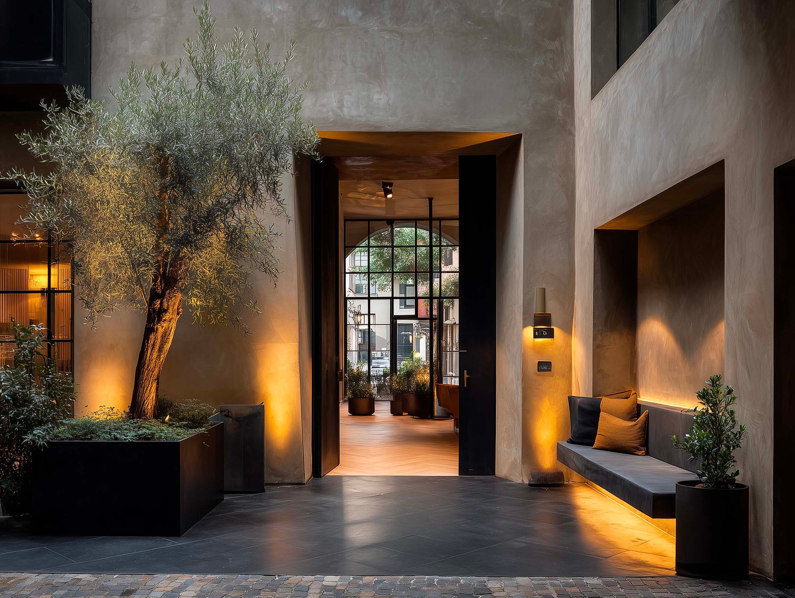 Soglia di ingresso di hotel boutique a Milano — olivier sculturale, banquette in pietra e luce calda serale, Paracelsus Gardens™