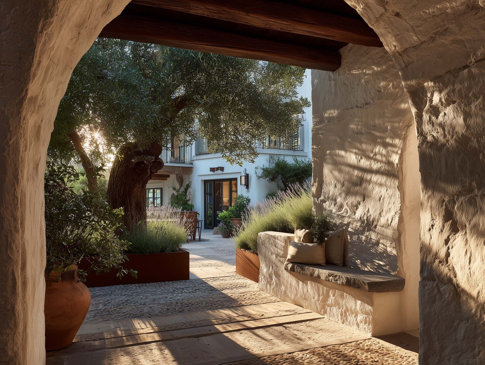 Percorso di ritorno nel giardino aromatico — arco in pietra, fioriere Corten con Lavandula, olivier centenario e vista sulla facciata dell'hotel, transizione sensoriale lenta, Paracelsus Gardens™