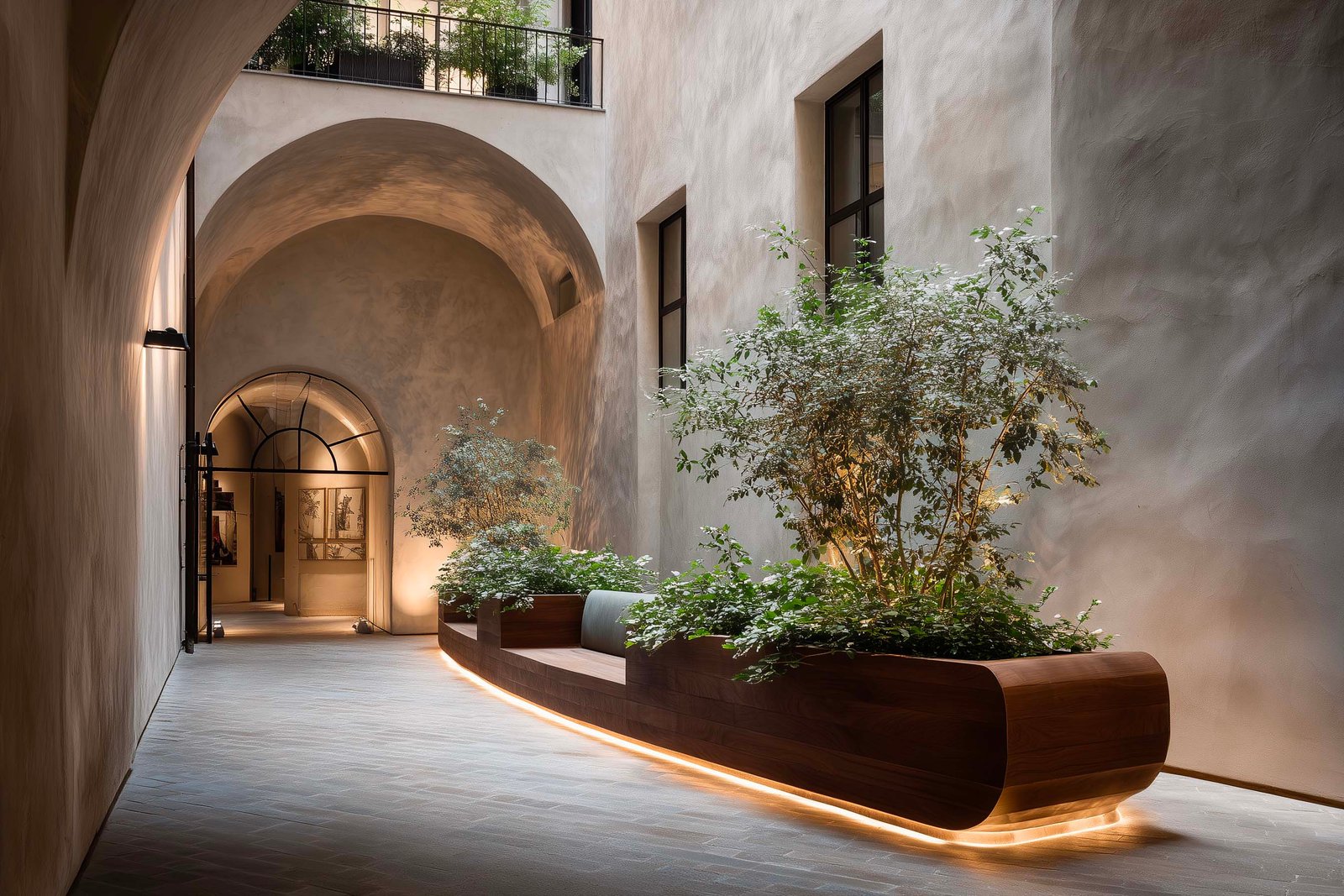 Passaggio stretto in palazzo milanese con fioriera Lignum in noce affumicato e Laurus nobilis, pavimento in Pietra Serena, LED integrato — Paracelsus Gardens™